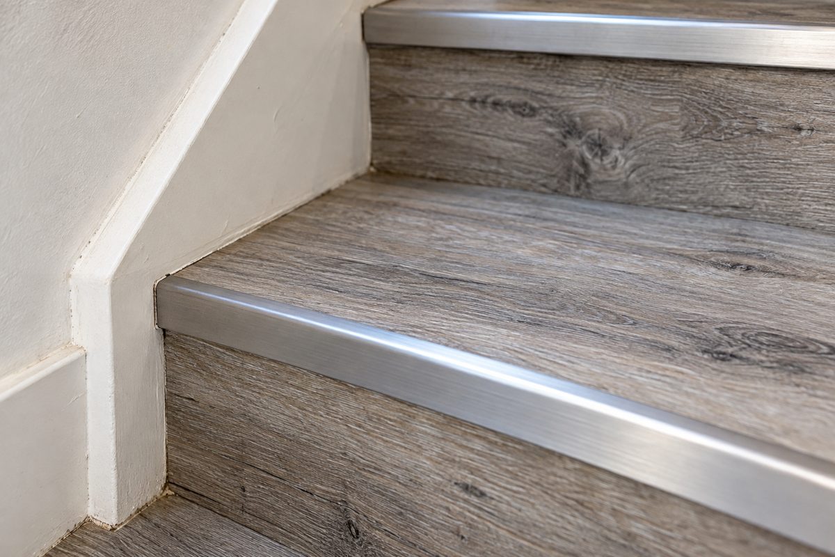 Custom luxury vinyl plank stair tread installation with flush anodized stair nosing and tight stringer cuts